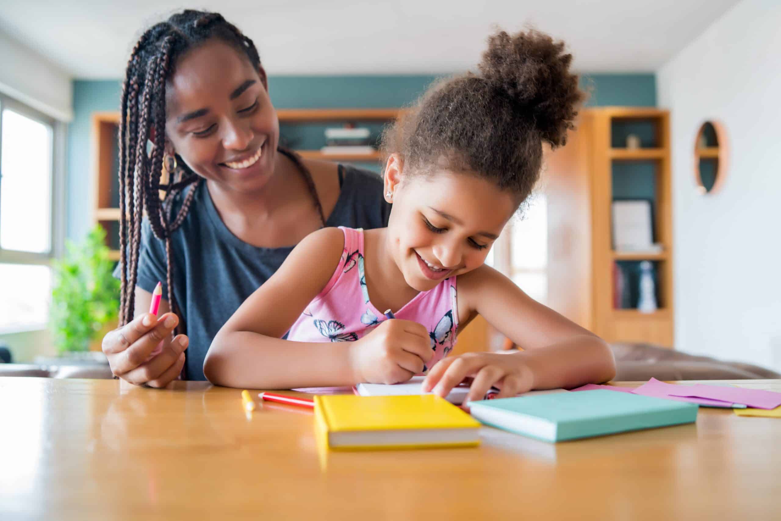 Mãe ajudando sua filha com atividades escolares.